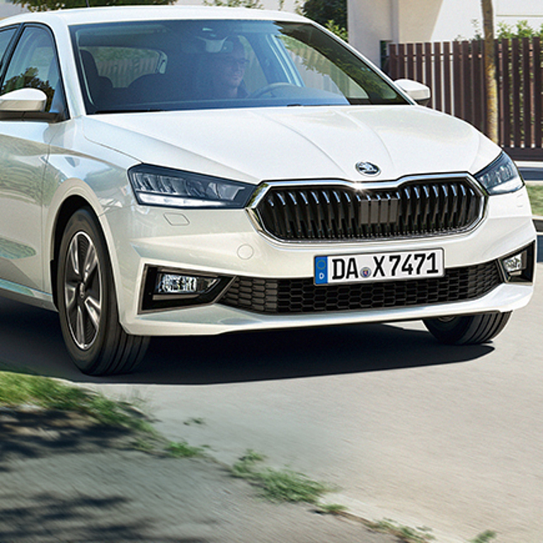 Auf dem Bild sehen Sie rechts eine Frau mit einem Umschlag in der Hand un dlinks den Škoda Fabia als Symbol für die Škoda Pflegedienste Aktion